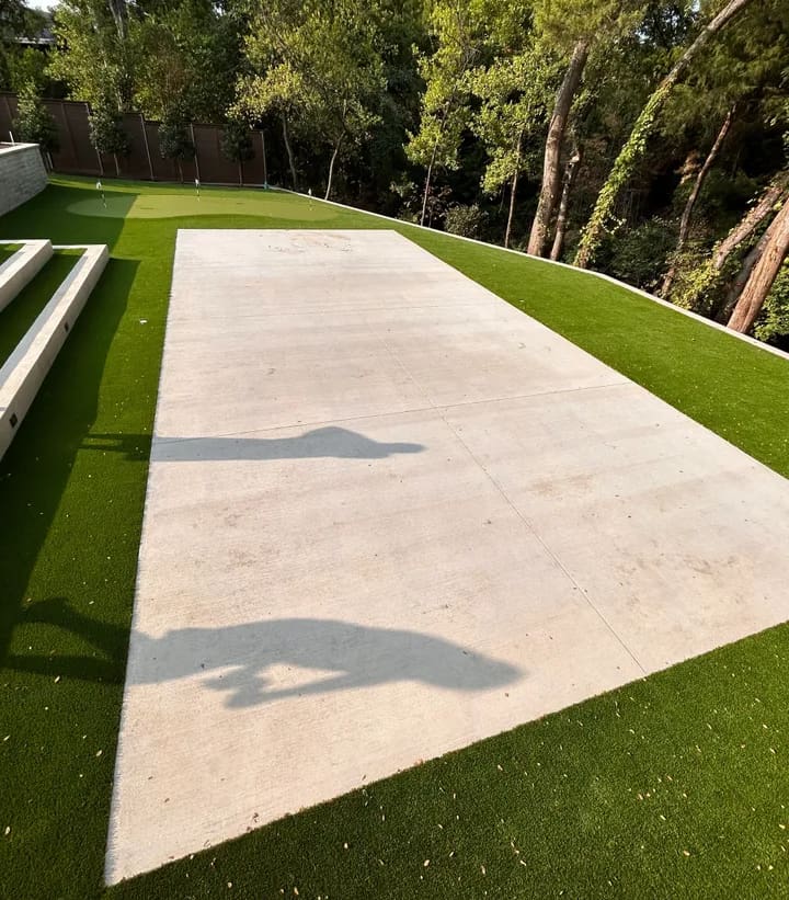 A view of a white concrete slab and some grass.